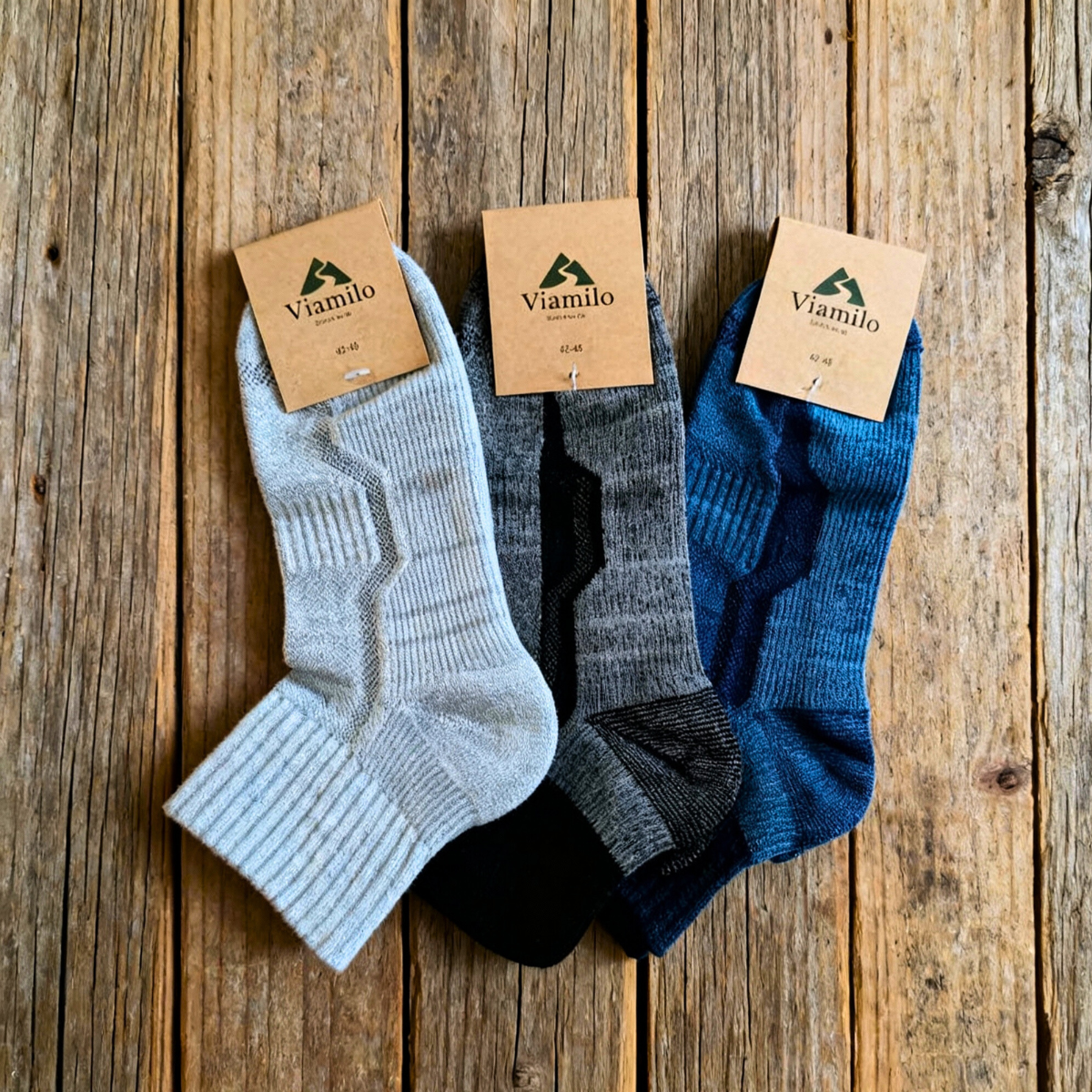 Viamilo Merino-Wandersocken in Grau, Blau und Schwarz mit Produktetiketten auf Holzhintergrund