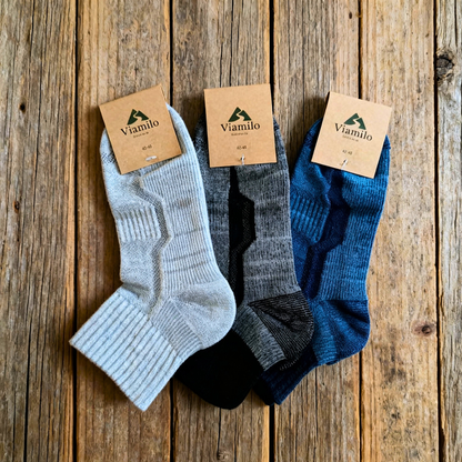 Viamilo Merino-Wandersocken in Grau, Blau und Schwarz mit Produktetiketten auf Holzhintergrund