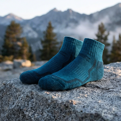 Blaue Merino-Wandersocken von Viamilo auf einem Felsen vor einer Berglandschaft