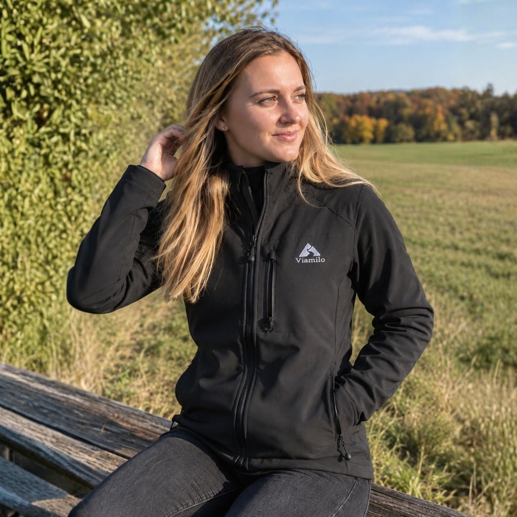 Frau trägt schwarze Viamilo Softshelljacke bei einer Pause draußen in der Natur