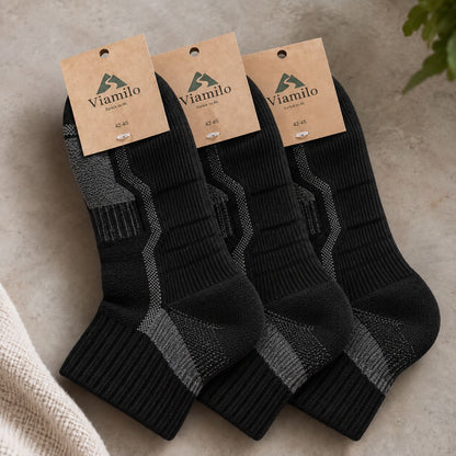 Drei Paar schwarze Viamilo Merino-Wandersocken mit Produktetiketten auf hellem Hintergrund
